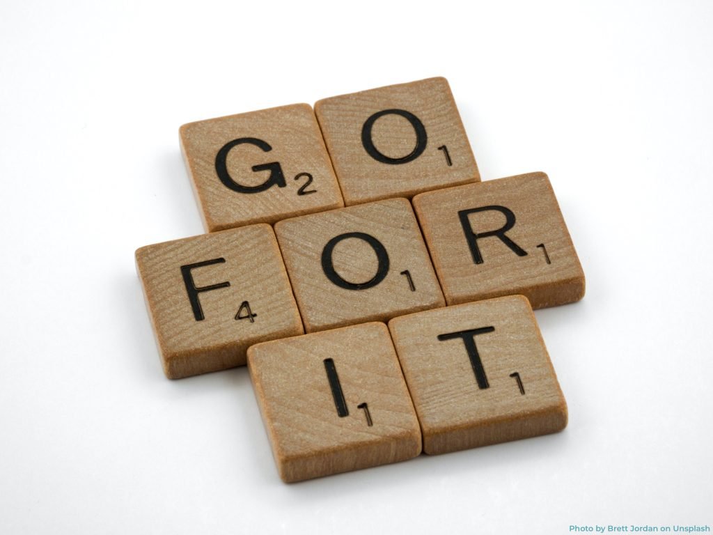 Scrabble game board with tiles spelling "go for it" and "secret weapon" highlighted in vibrant colors.